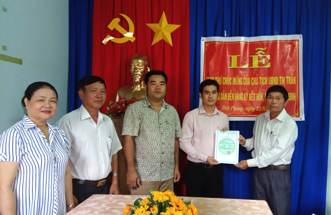 ông Nguyễn Trì, phó bí thư, chủ tịch HĐND thị trấn Đức Phong trao giấy khai sinh cho người dân tại lễ ra mắt mo hình